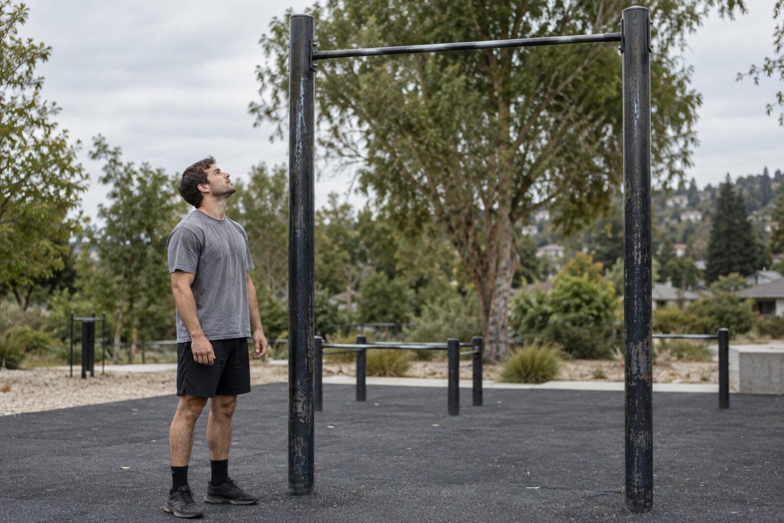 Man standing beside a freestanding outdoor pull-up bar.